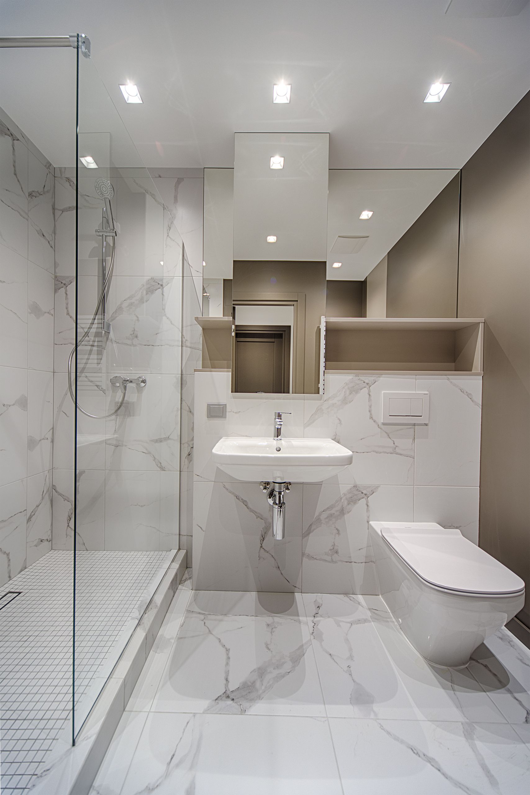 Interior of stylish light bathroom with white sink and toilet and built in shower cabin